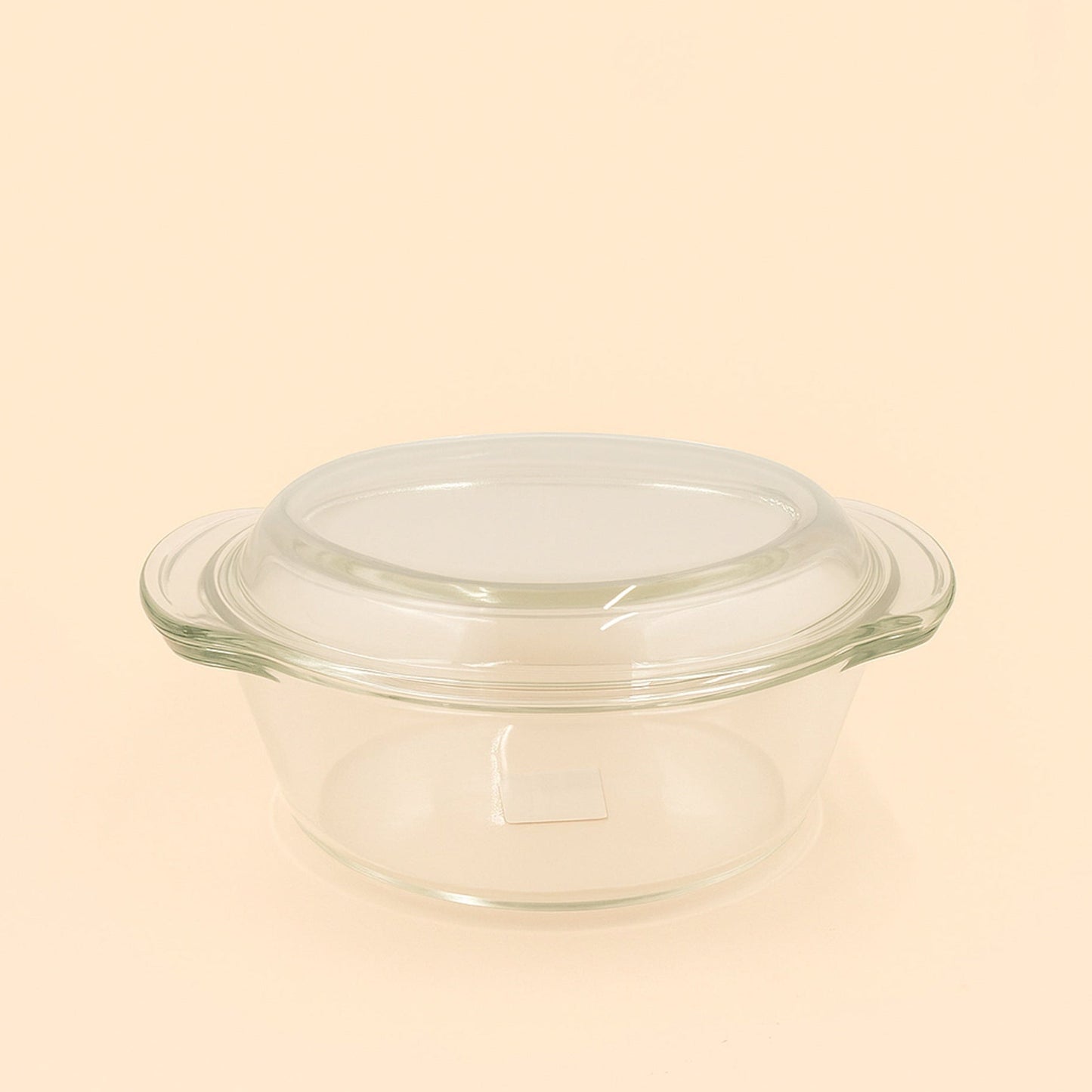 Clear glass baking dish with lid on a beige background