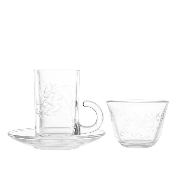 Clear glass cup with saucer and additional cup on a white background