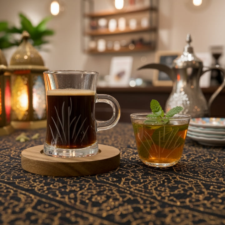Two glasses of hot beverages on a patterned tablecloth with a blurred background