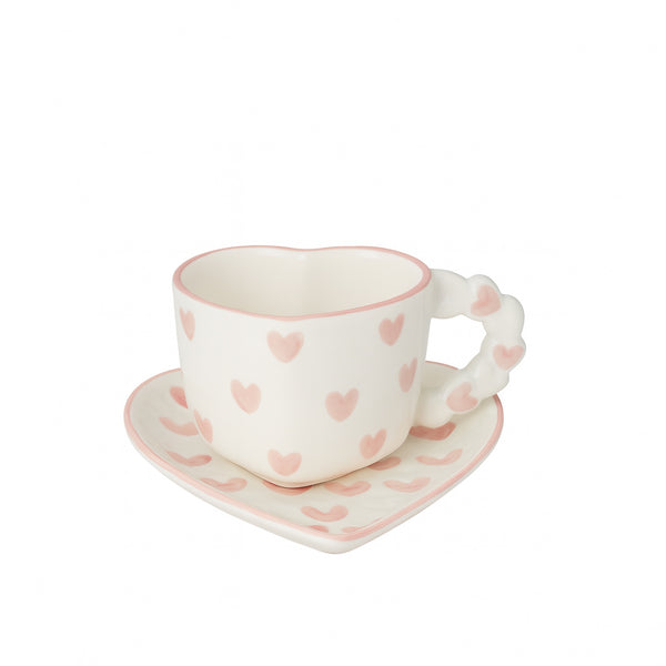 Ceramic cup and saucer with pink heart patterns on a white background