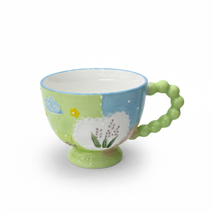 Colorful ceramic mug with a green handle on a white background