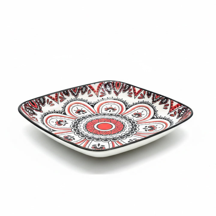 Decorative square plate with red and black patterns on a white background