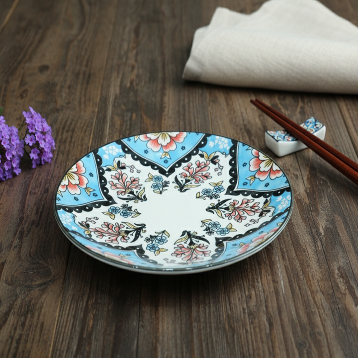 Decorative ceramic plate with floral patterns on a wooden surface with chopsticks and a napkin.
