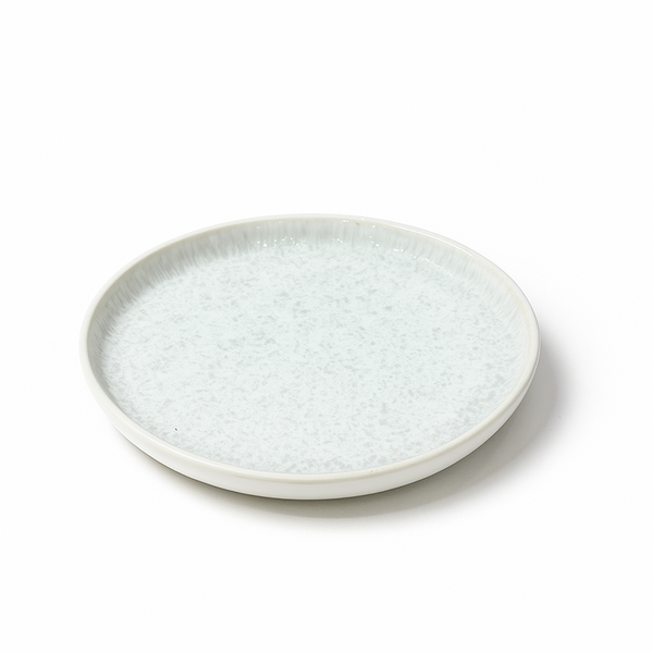 Round ceramic plate with textured surface on a white background