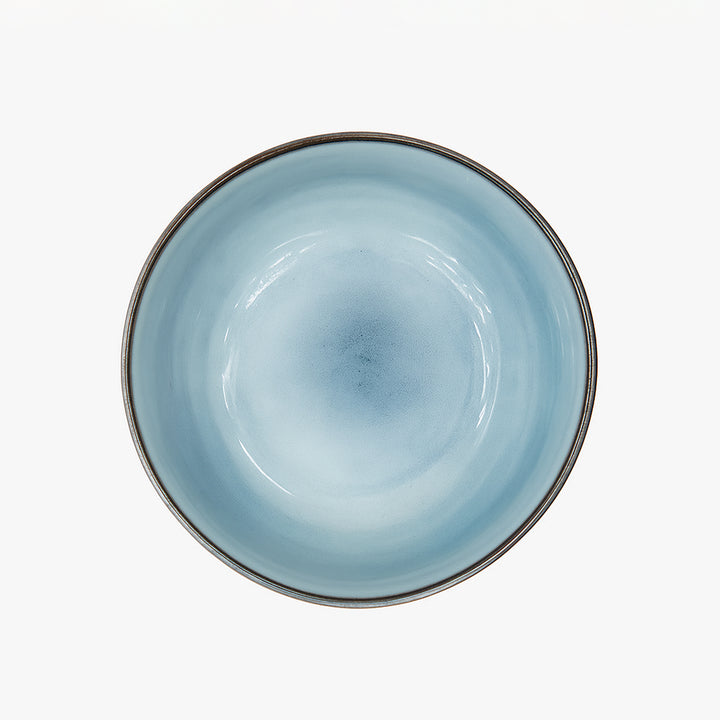 Ceramic bowl with a light blue interior and metallic rim on a white background