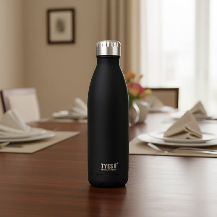 Black insulated bottle with silver cap on a dining table
