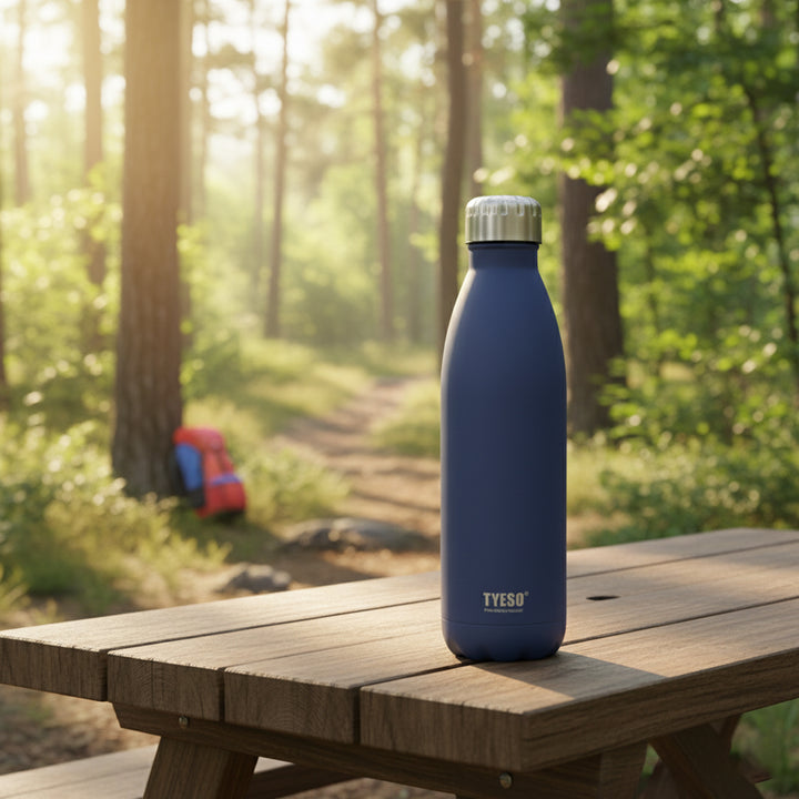Blue water bottle with silver cap on a wooden table in a forest