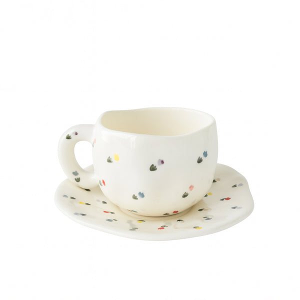 Ceramic cup and saucer with colorful polka dot design on a white background