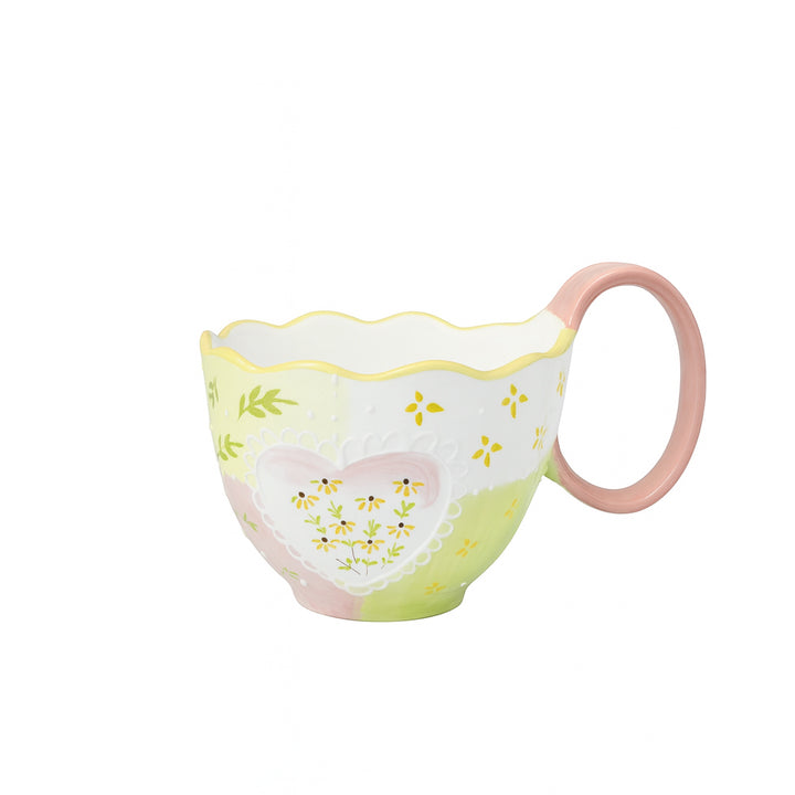 Ceramic cup with a white, yellow, and green floral embossed heart design, scalloped rim, and pink handle — displayed on a white background from Siddiq Gifts, Mussafah Abu Dhabi.