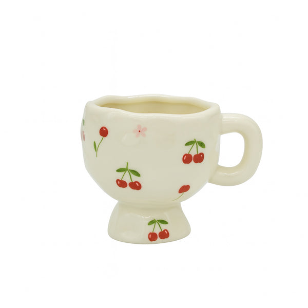 Ceramic mug with a white finish featuring a red cherry and pink flower pattern, rounded handle, and pedestal base — displayed on a clean white background from Siddiq Gifts, Mussafah Abu Dhabi.