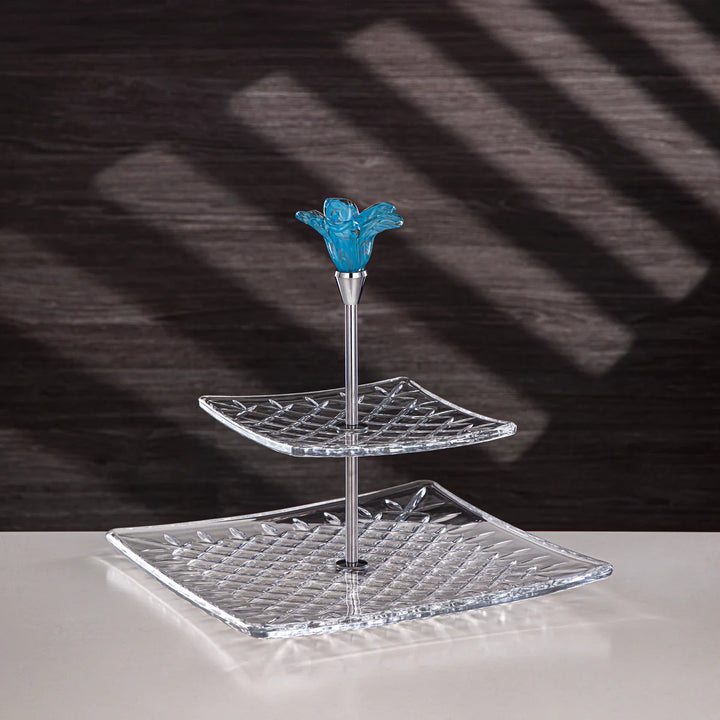 Two-tiered crystal stand with blue floral finial on a dark background