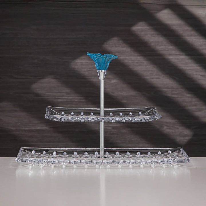 Two-tiered crystal stand with a blue floral top piece on a dark background