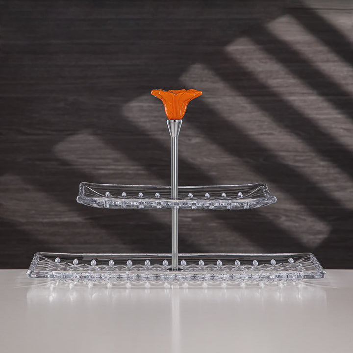 Two-tiered clear glass stand with an orange top piece on a dark background