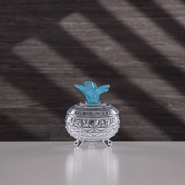 Clear glass container with a blue angel figurine on a textured gray background