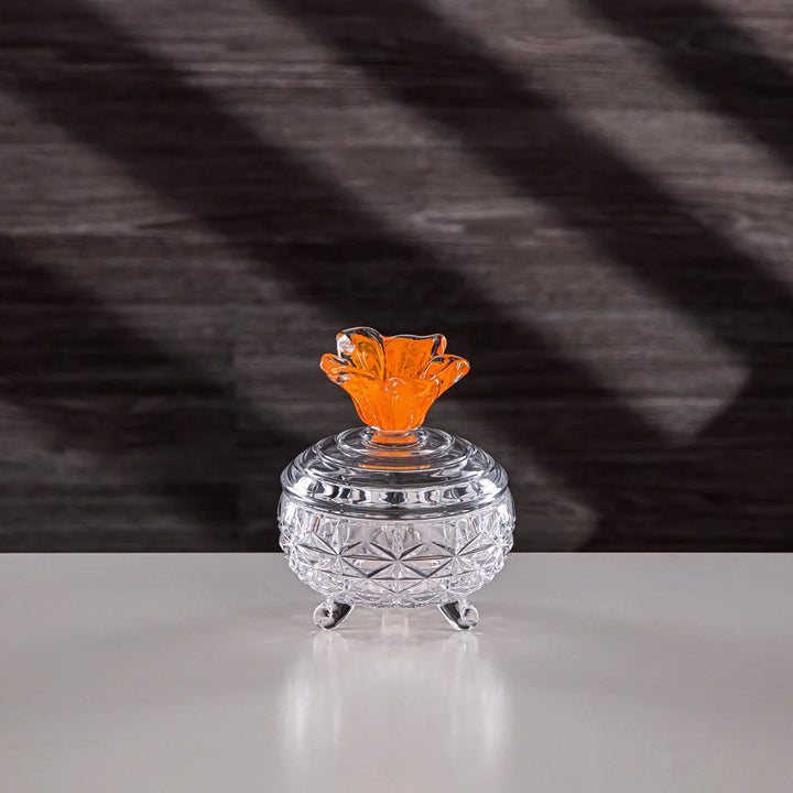 Clear glass container with an orange lid on a dark textured background