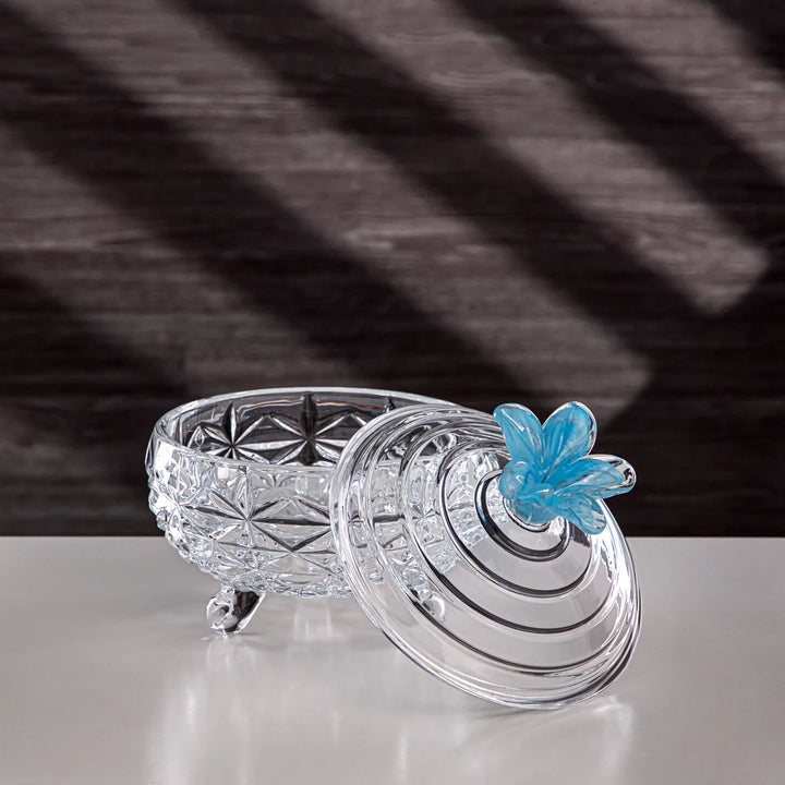 Decorative crystal object with a blue flower on a reflective surface