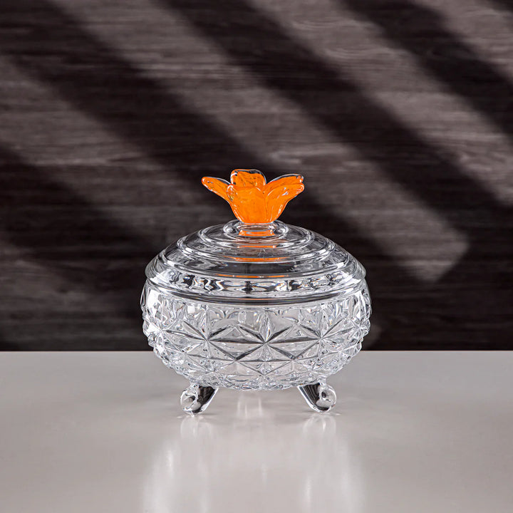Clear glass trinket dish with an orange butterfly lid on a dark background