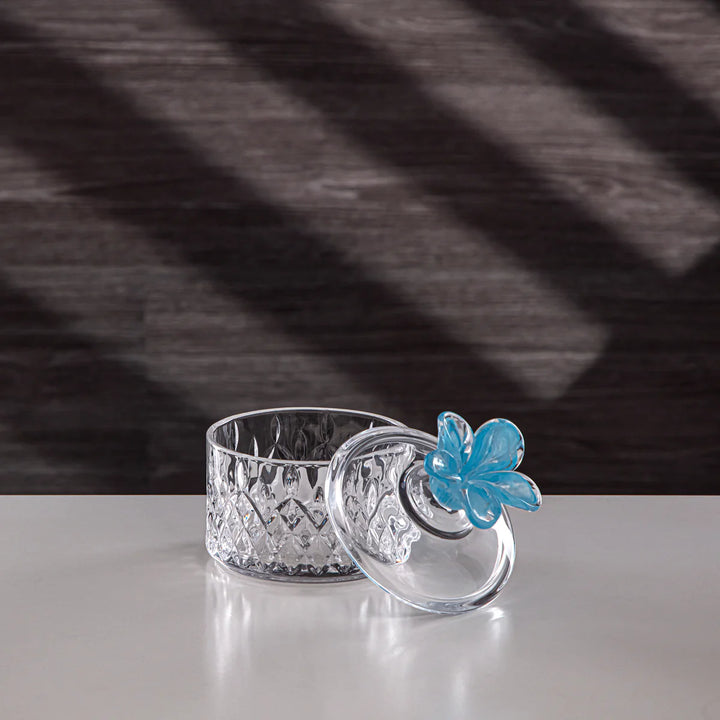 Crystal candle holder with a blue butterfly accent on a reflective surface.