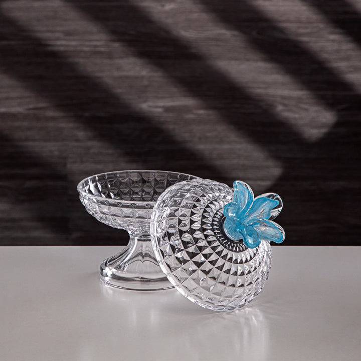 Clear glass container with blue flower design on a black and white striped background