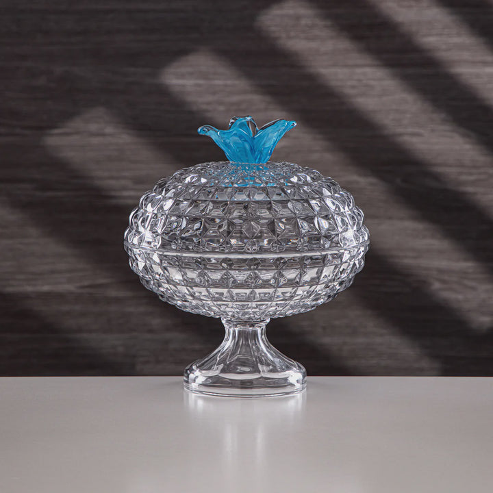 Clear glass container with a blue lid on a reflective surface and dark background