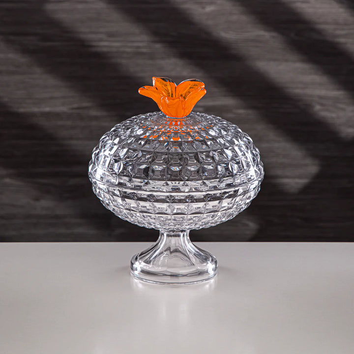 Clear glass container with an orange lid on a dark background