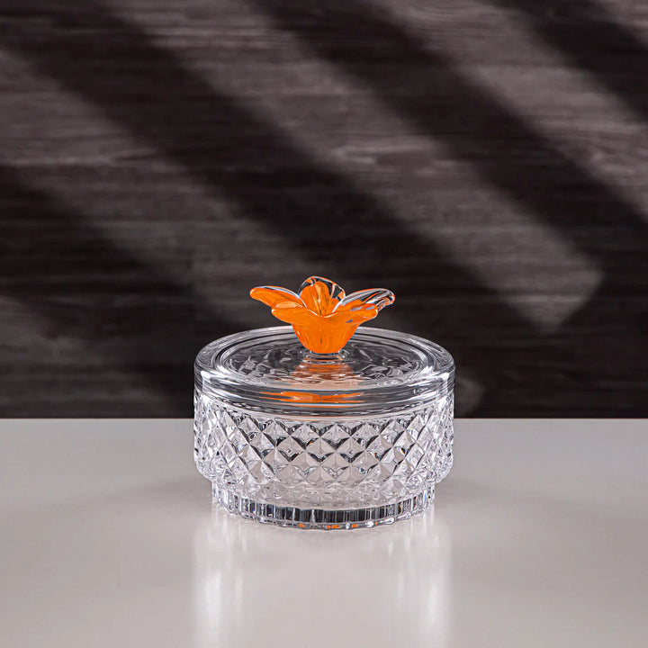 Clear glass container with an orange butterfly on a textured gray background