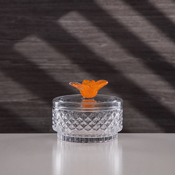 Clear glass container with an orange butterfly on a textured dark background