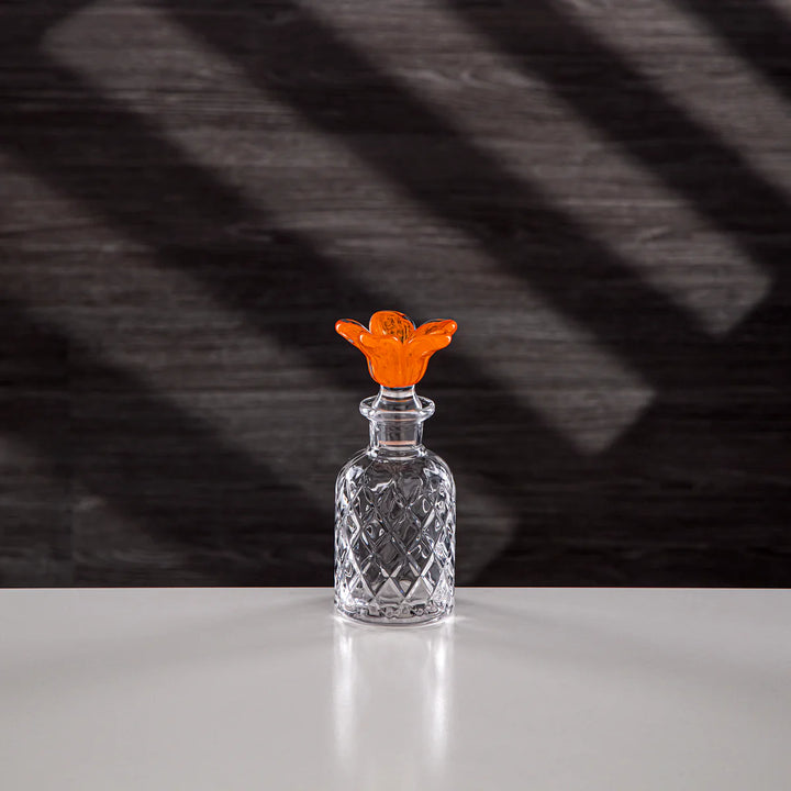 Clear glass bottle with an orange stopper on a dark textured background