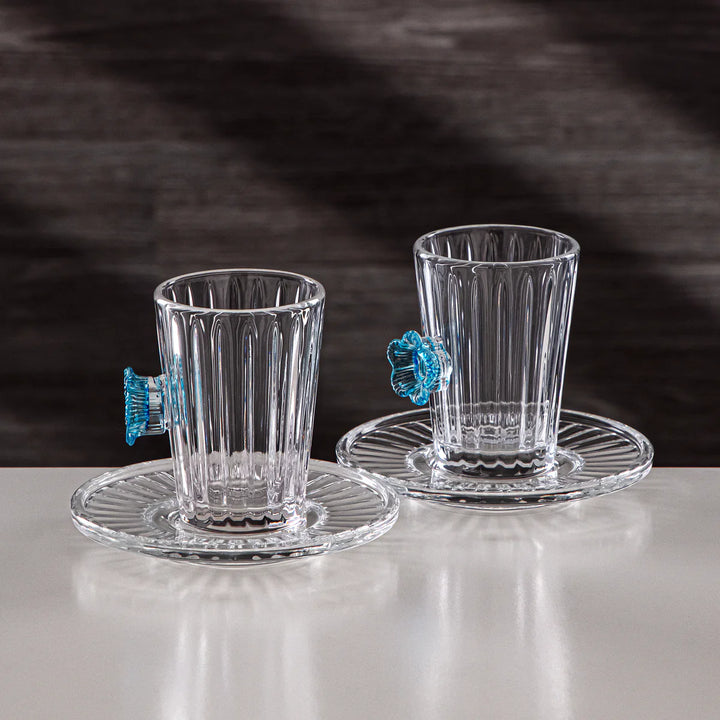 Two clear glass tumblers with decorative handles on a white surface.