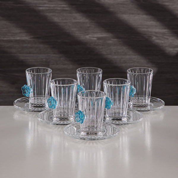 Set of six clear glass tumblers with decorative blue elements on a white surface and dark background