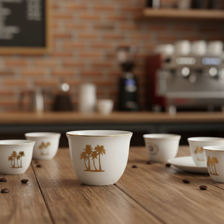 White ceramic cups with palm tree design on a wooden table in a coffee shop setting.