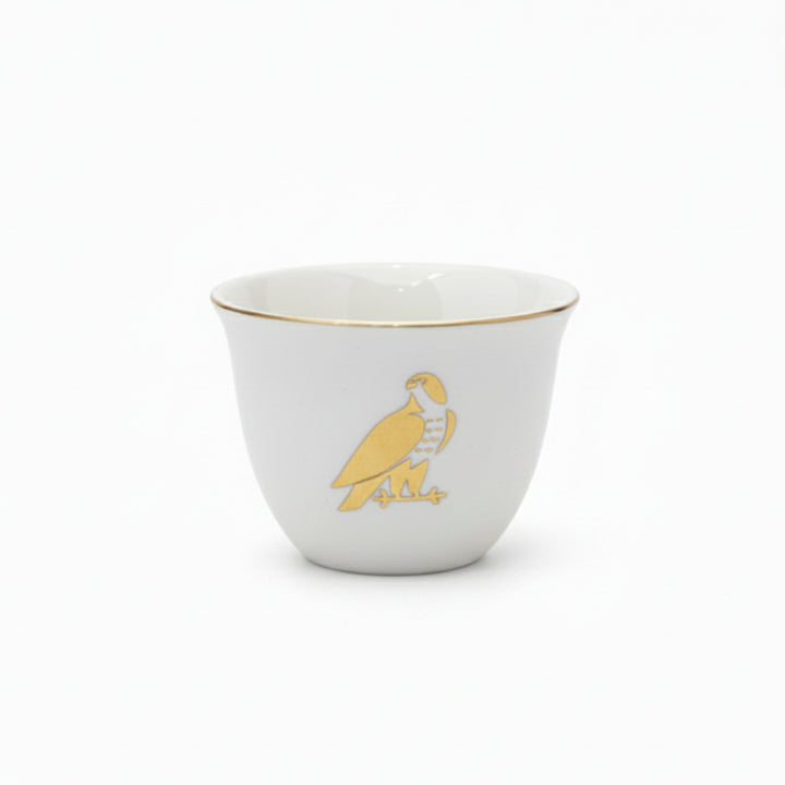 White cup with gold rim and parrot design on a white background