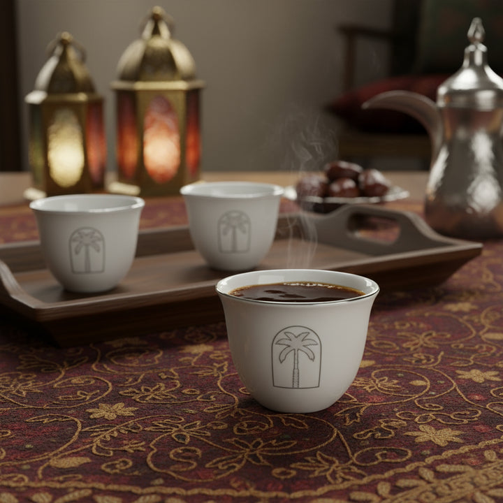 Cup of steaming coffee on a patterned tablecloth with decorative lanterns and teapot in the background.