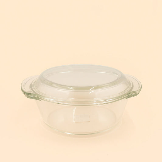 Clear glass baking dish with lid on a beige background

