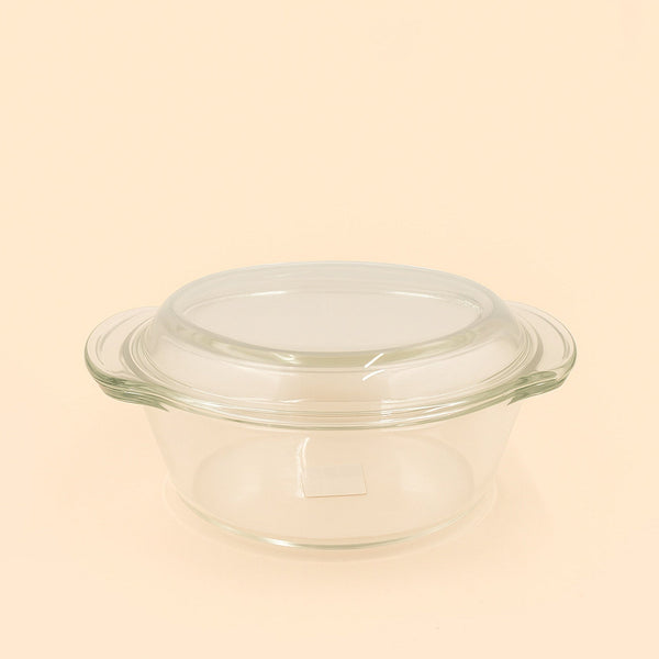 Clear glass baking dish with lid on a beige background

