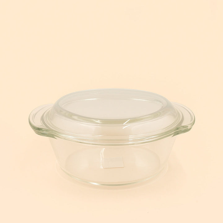 Clear glass baking dish with lid on a beige background

