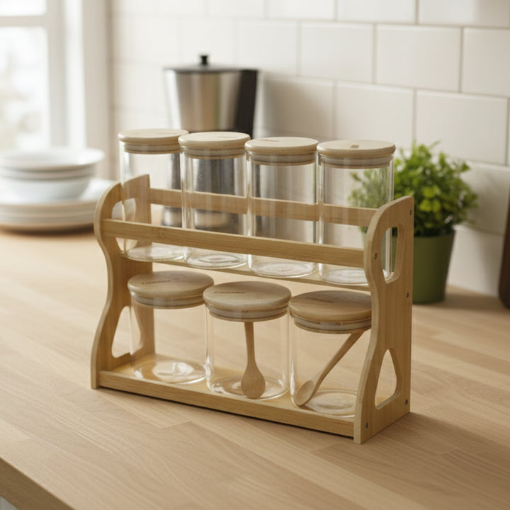 Wooden spice rack with glass jars and wooden spoons on a kitchen counter.