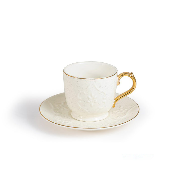 White ceramic cup with gold handle and saucer on a white background