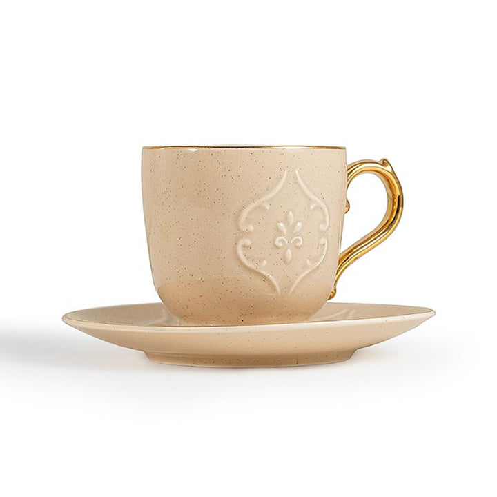 Beige ceramic cup with gold handle and saucer on a white background