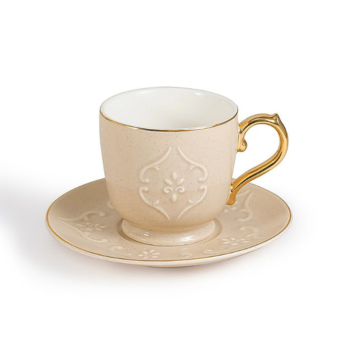 Cream-colored teacup with gold handle and saucer on a white background