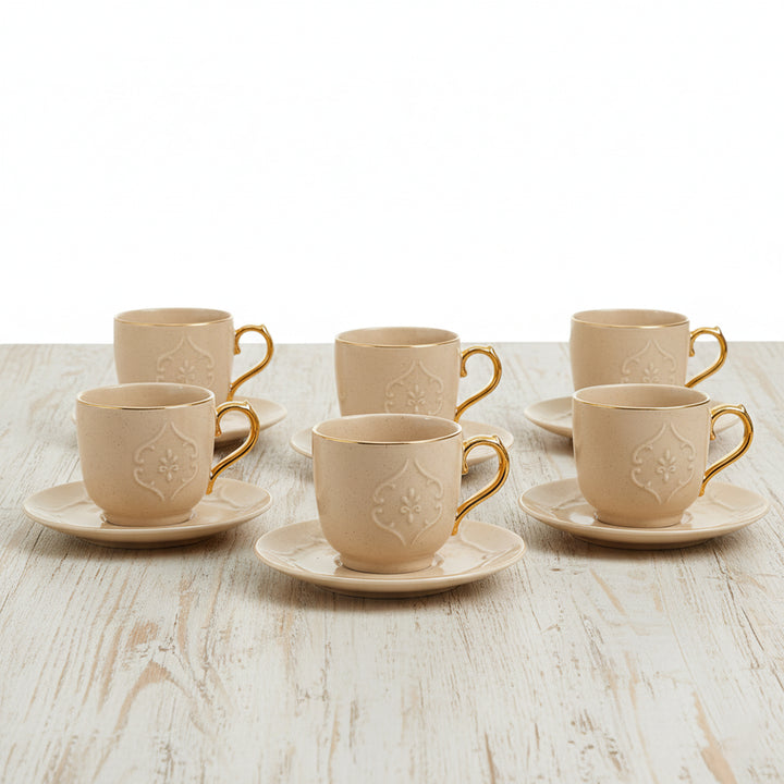 Set of beige ceramic cups with gold accents on a wooden table