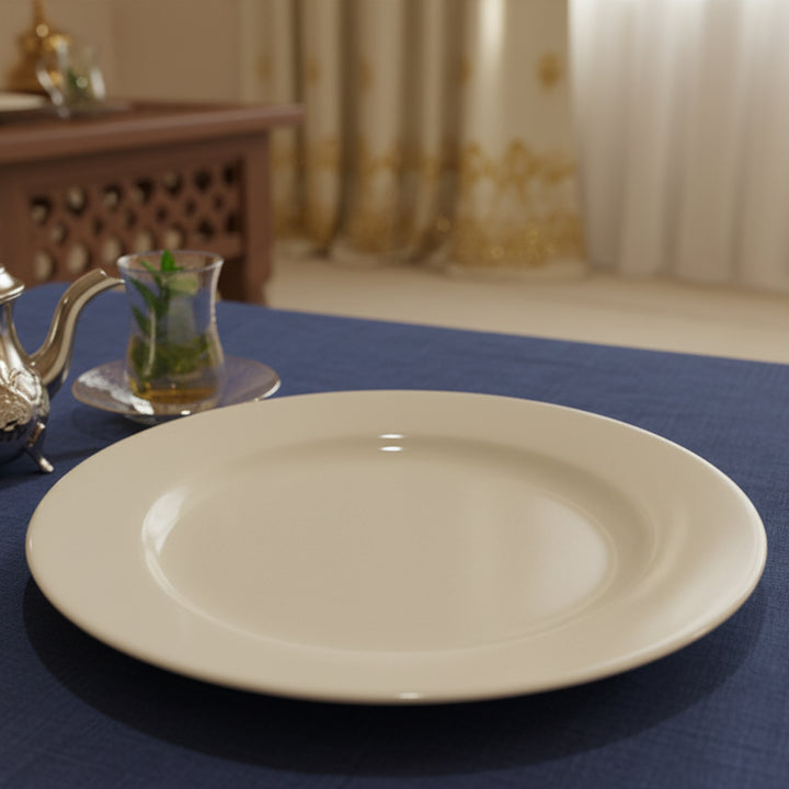 White plate on a blue tablecloth with a teapot and glass in the background