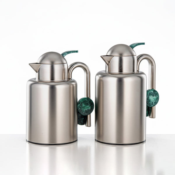 Two stainless steel oil and vinegar dispensers with green marble ends on a white background