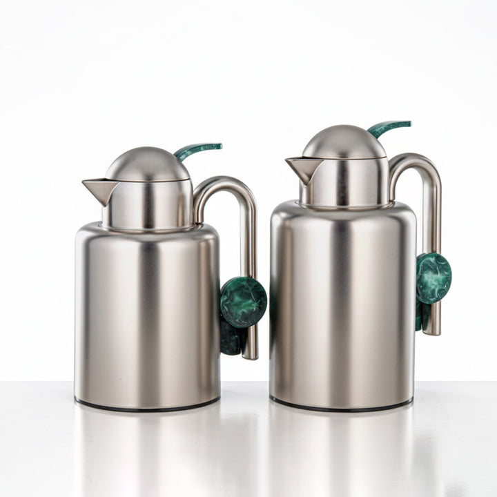 Two stainless steel oil and vinegar dispensers with green marble ends on a white background