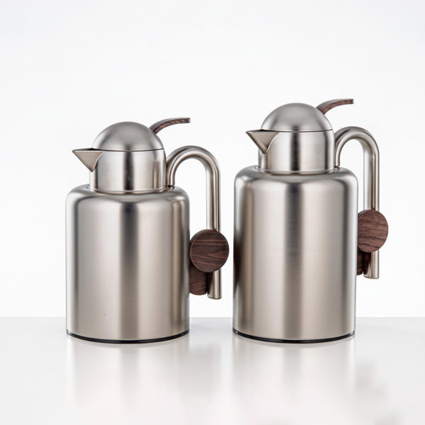 Two stainless steel pitchers with wooden handles on a white background