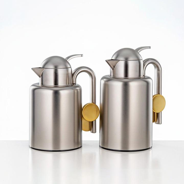 Two stainless steel oil dispensers with gold accents on a white background