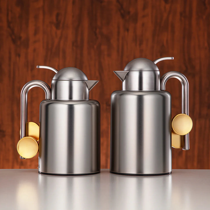 Two stainless steel oil dispensers with gold accents on a white background