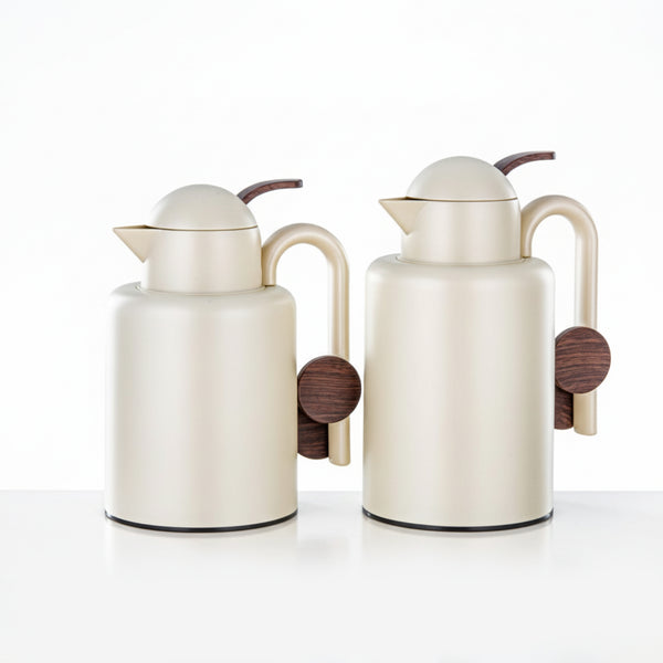 Two cream-colored ceramic pitchers with wooden handles on a white background
