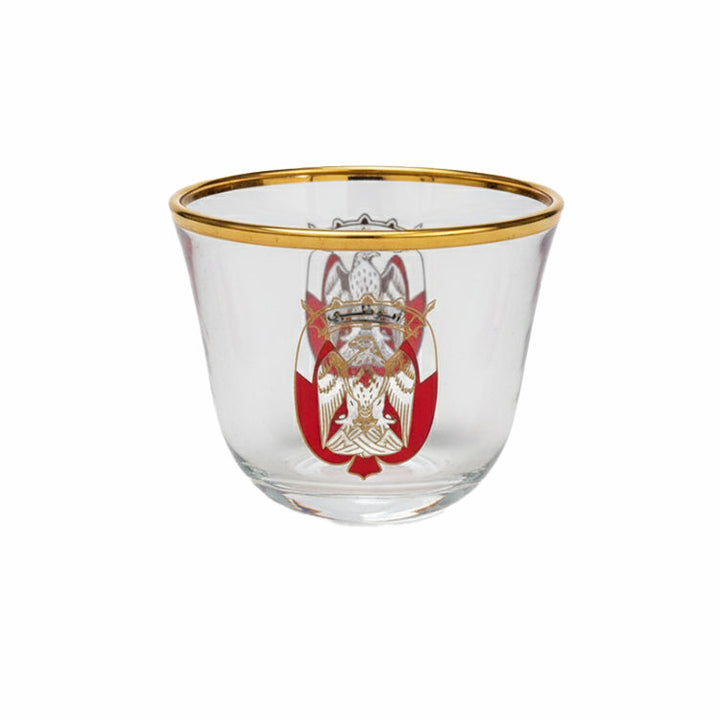 Clear glass with gold rim and red emblem on a white background