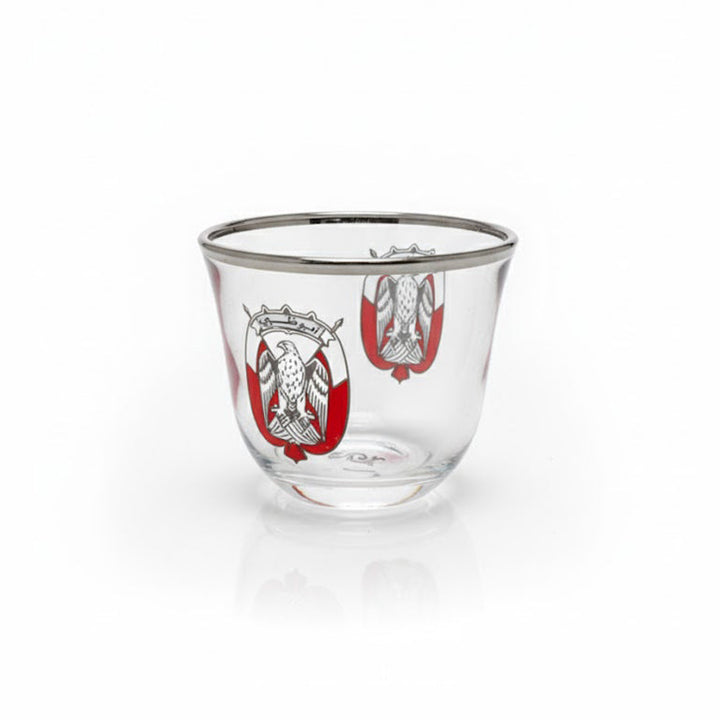 Clear glass tumbler with red and silver design on a white background